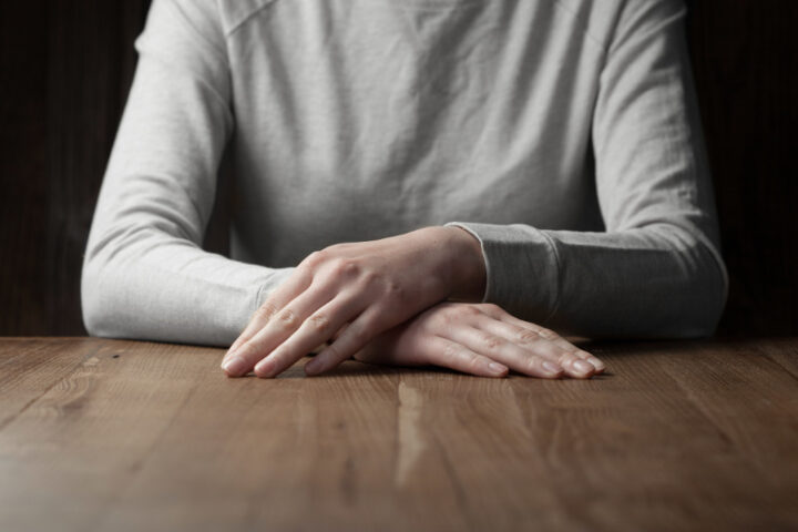 woman arms folded over wooden background wearing grey sweater
